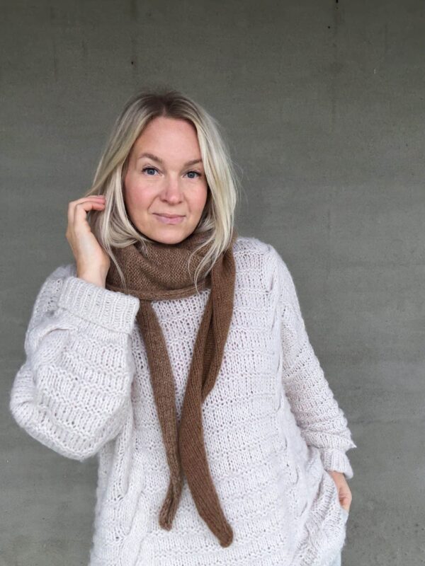The Crown Hood Scarf by PoolaKnits is knitted in Ruukin kehräämö Alpakka in colorway Light Camel. The closest match in our selection is Sandnes Garn Alpakka Ull in color 2650 Grey Beige Heather.