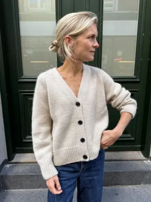 The white Champagne Cardigan is knitted in Double Sunday by Sandnes Garn in the color Almond [2511] held together with Tynn Silk Mohair by Sandnes Garn in the color Kitt [1015].
