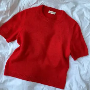 The red Poppy Tee is knitted in Cashmere Classic by Cardiff in the color Hermes [517].